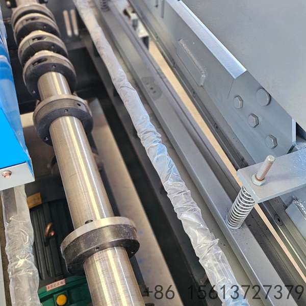 Blue industrial coil leveling and roll forming machine in a factory workshop with green floor markings.